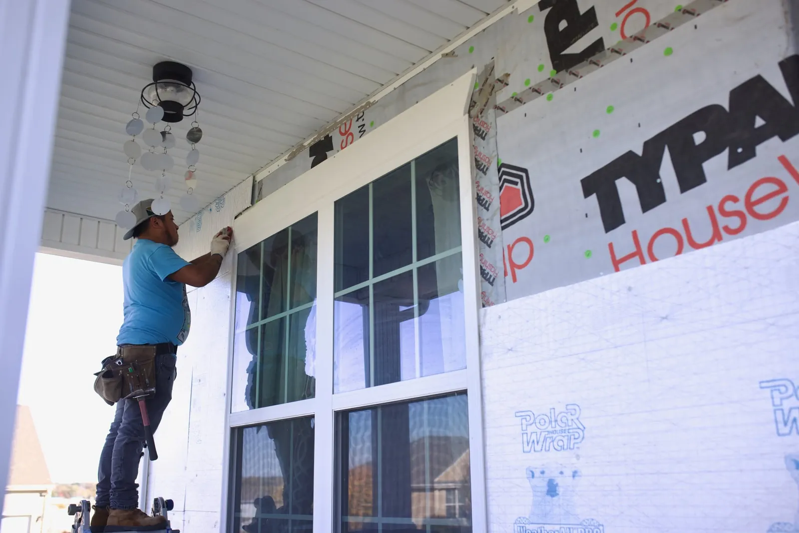 A Monarch installer fitting trim around a new window on a ladder
