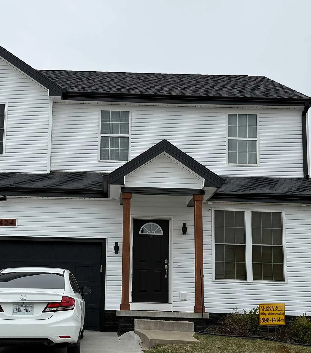 A finished Monarch home with a black entry door and a Monarch yard sign
