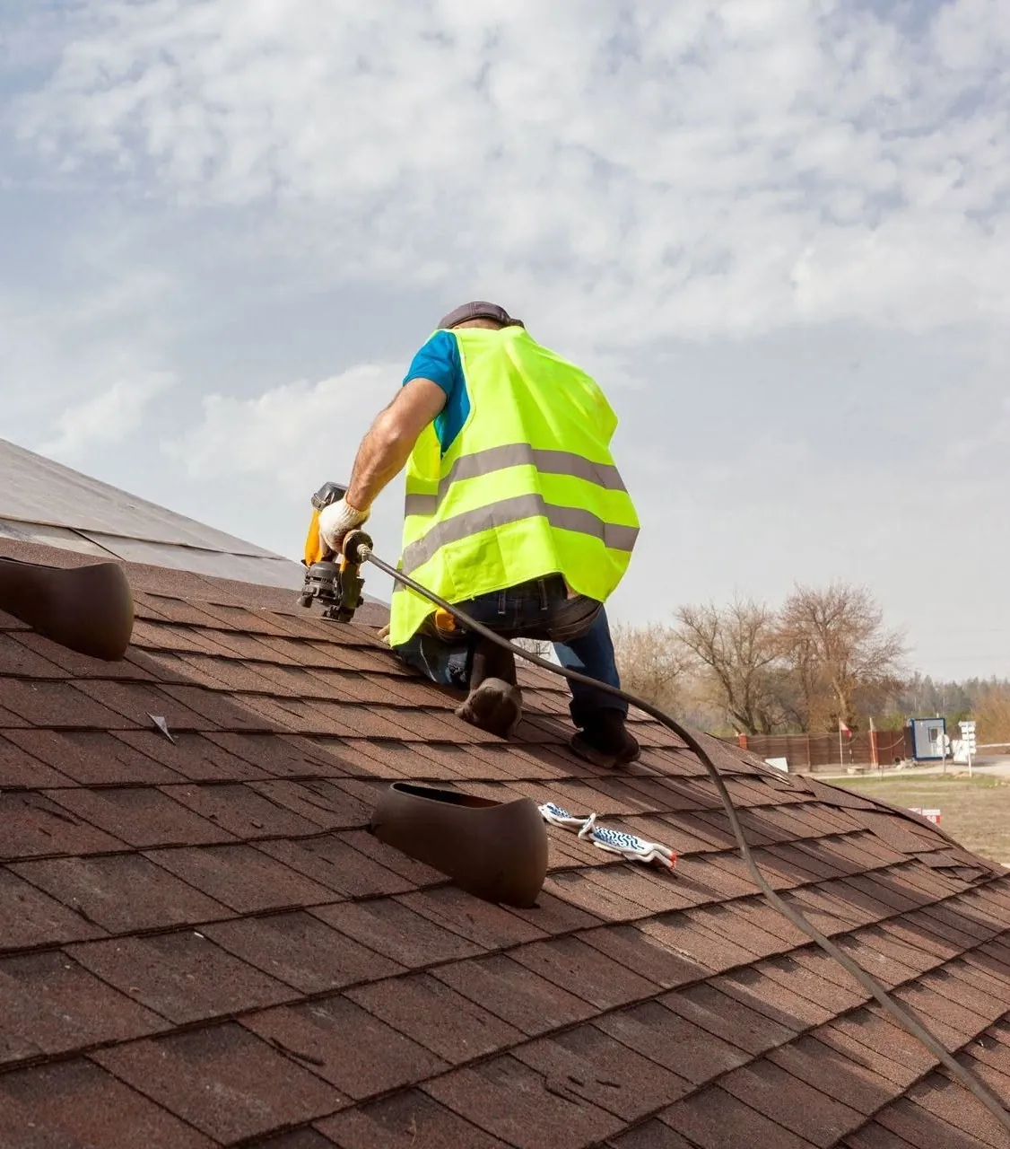 A roofer nailing new shingles on a residential roof