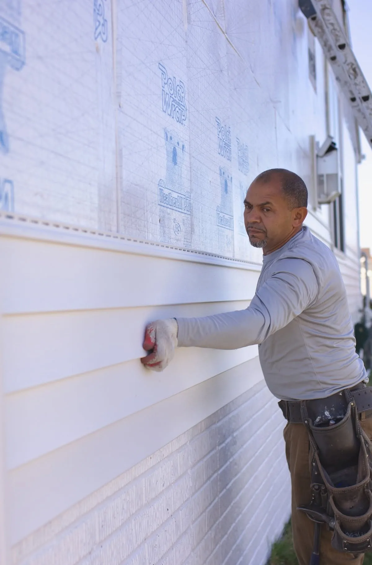 A Monarch installer hanging new siding over house wrap