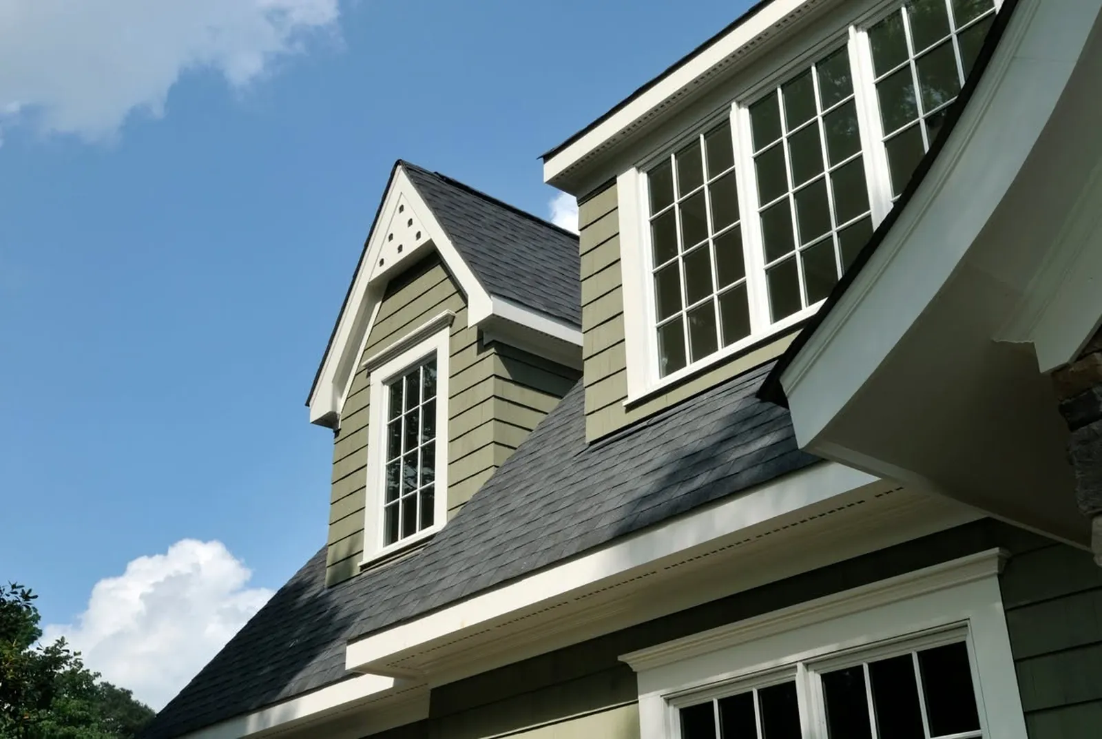 Gray dormers with white-trimmed windows on a green-sided home