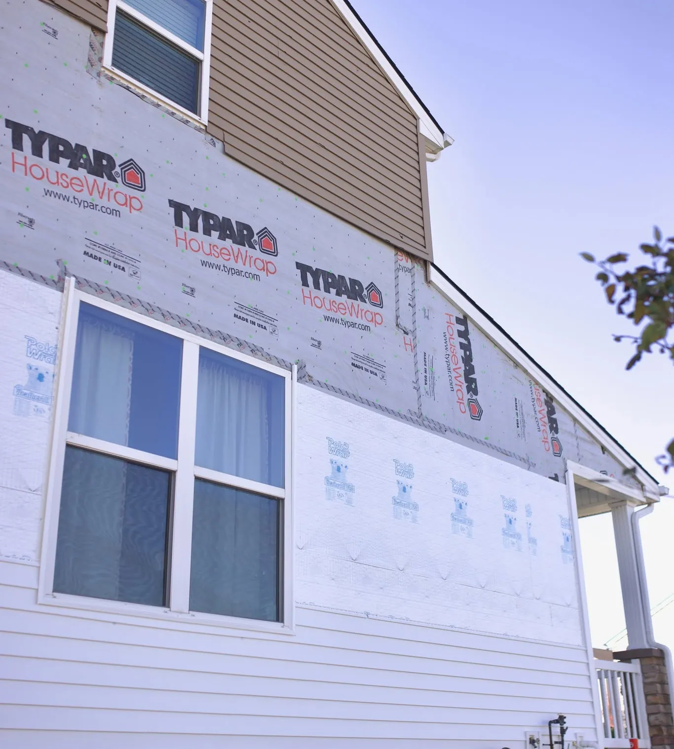 House wrap going up behind new windows during a siding replacement