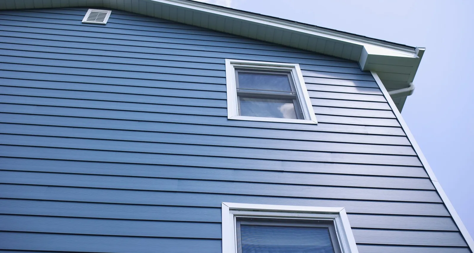 Blue lap siding with white window trim on a two-story home