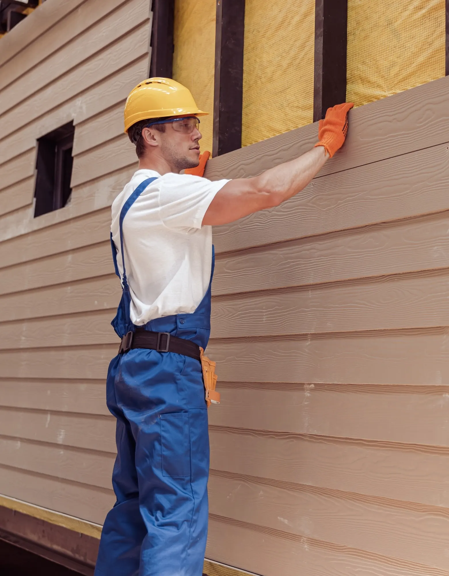 An installer fitting wood-grain lap siding over house wrap