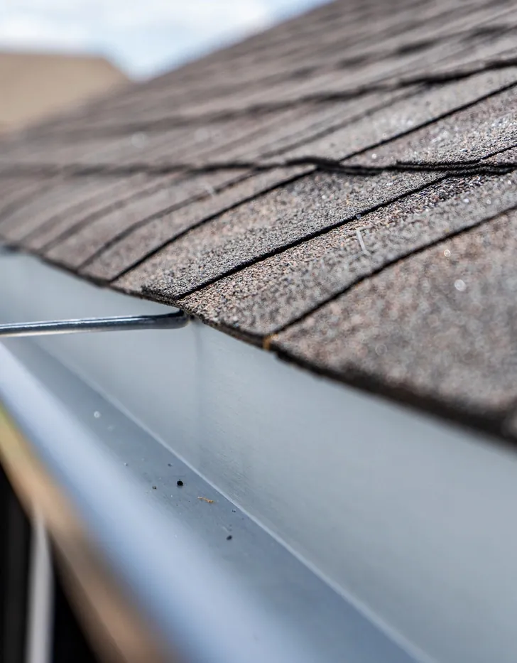 A seamless gutter running along the edge of a shingle roof